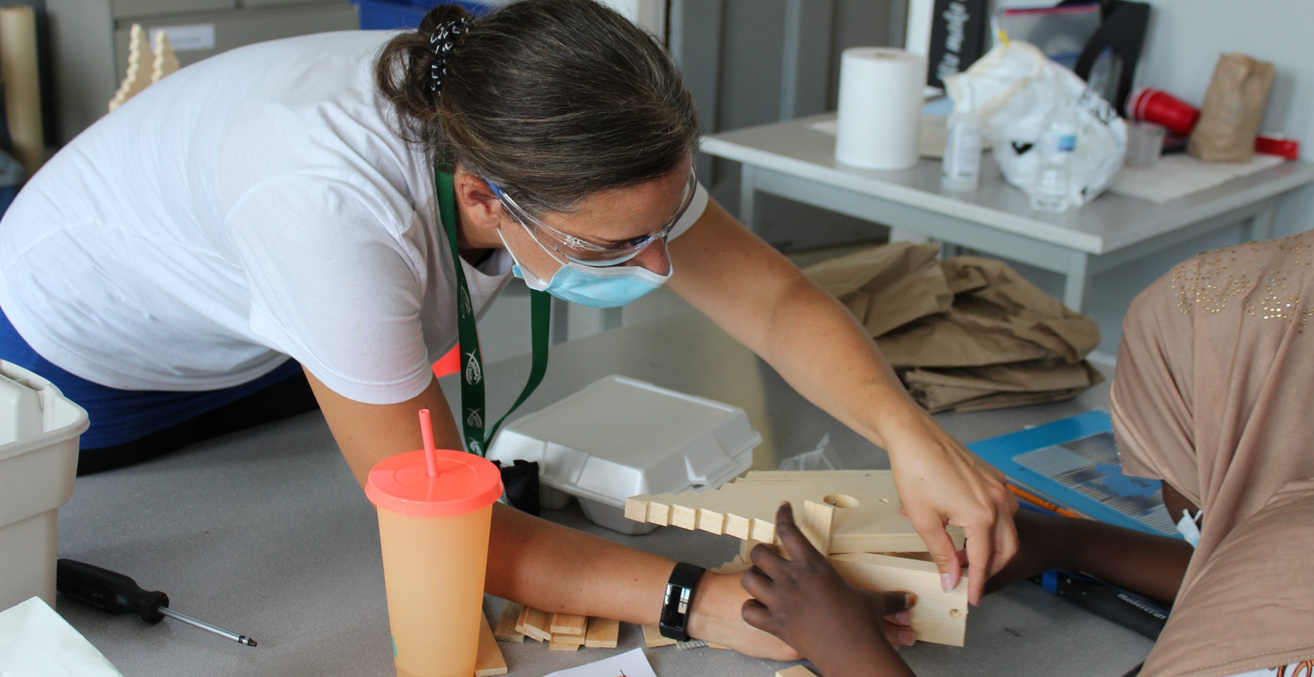 A youth staff helping a student build a bird house