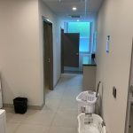 Photo looking into a recently renovated washroom. Two white laundry baskets sit on the floor to the right of the photo. Two doors open on the upper left hand side of the photo, opening into private accessible shower stalls.