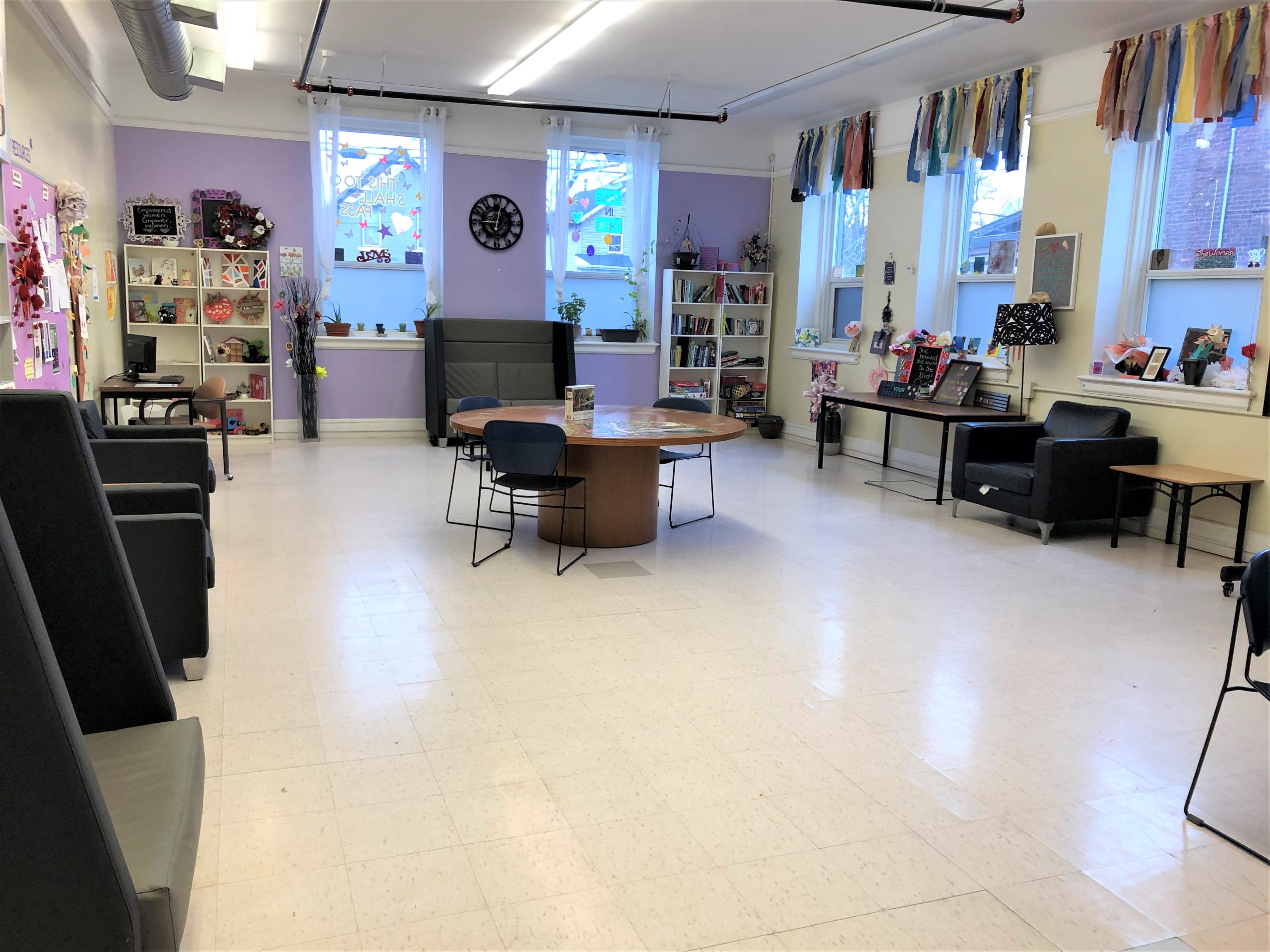 A common room for Willow's Place - a community hub for women. The space is filled with furniture for relaxing, playing games, and more. It is painted and decorated so it is welcoming and bright.