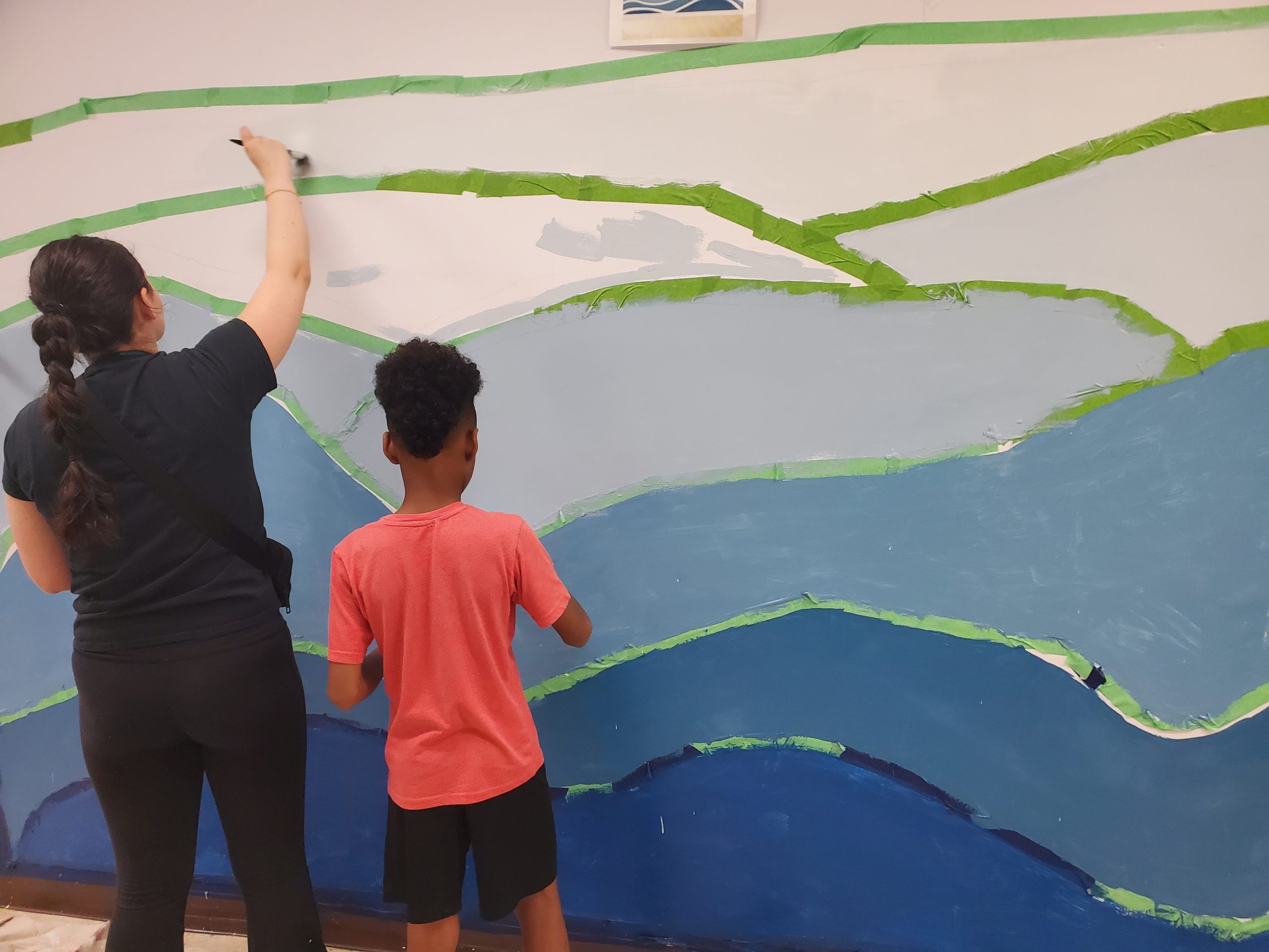 Two people painting a mural