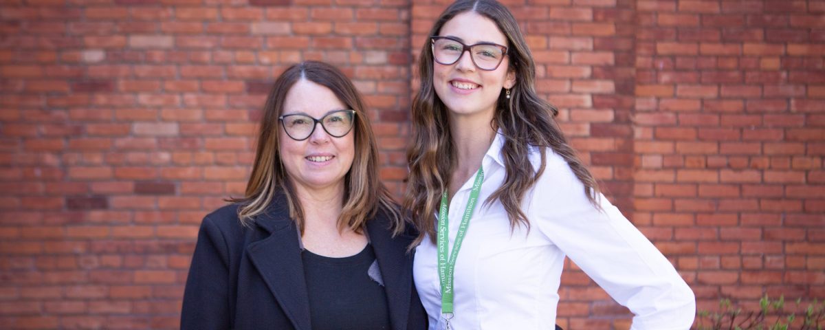 a photo of Payton and her mother Jenn standing side by side in front of a brick building